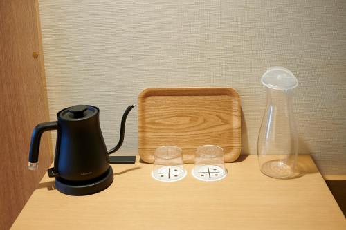 a table with a coffee maker and a blender and glasses at Umekoji Potel KYOTO in Kyoto