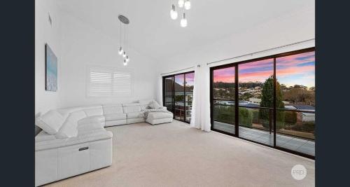 a white living room with a couch and large windows at Aquablue Holiday Home - Hot Spa & Pool - 2m Walk to Beaches in Corlette