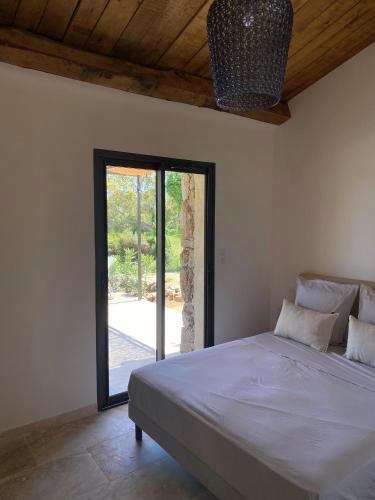- une chambre avec un grand lit et une porte en verre dans l'établissement Villa de charme avec piscine, à Sotta