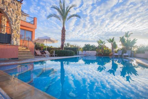 a swimming pool with palm trees and a building at Villa Saraliana Sandy Beach Villas - Heated Pool - Jacuzzi - Private Beach Area in Polis Chrysochous