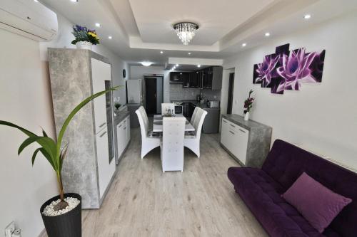 a kitchen and a living room with a table and a purple couch at Apartman Zemplinska Širava Timea in Kaluža