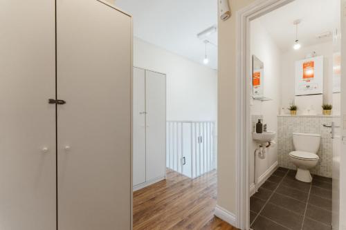 a bathroom with a toilet and a glass shower door at Mile End Rooms 57A in London