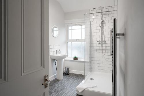 里亞格林的住宿－Wrea Cottage, 2 Bedrooms WiFi & Parking near Ribby Hall，白色的浴室设有水槽和淋浴。