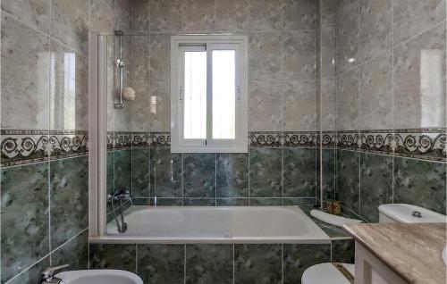 a bathroom with a tub and a window and two toilets at Stunning Home In Torre De Benagalbon With Outdoor Swimming Pool in Torre de Benagalbón