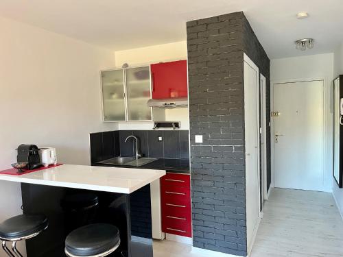 une cuisine avec des placards rouges et un mur en briques dans l'établissement Appartement résidence LA FREGATE - Pin Roland, à Saint-Mandrier-sur-Mer
