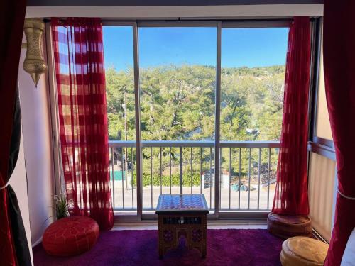 Cette chambre dispose d'une grande fenêtre avec des rideaux rouges. dans l'établissement Appartement résidence LA FREGATE - Pin Roland, à Saint-Mandrier-sur-Mer