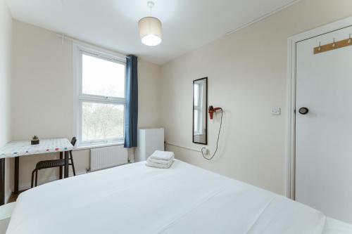 a white bedroom with a large bed and a window at Mile End Rooms 57A in London