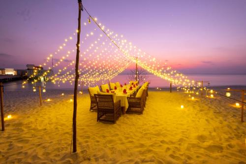 a dinner table on the beach with lights at Amilla Maldives in Kihaadhoo