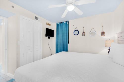 - une chambre blanche avec un lit blanc et un ventilateur de plafond dans l'établissement Sunbird 709W Beach Life, à Panama City Beach