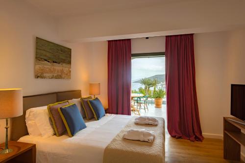 a bedroom with a bed and a large window at North Point Houses in Fiskardho