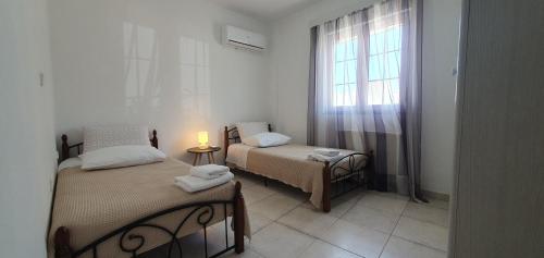um pequeno quarto com 2 camas e uma janela em Ailamakis Apartements em Zákros