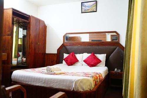 a bedroom with a bed with red pillows at Hotel Magnolia Mallroad Manali in Manāli