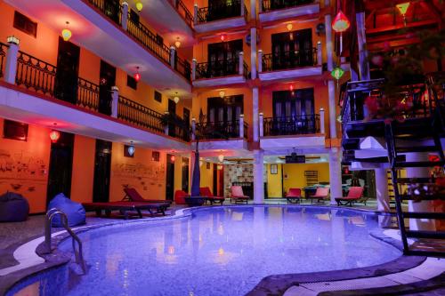 a large swimming pool in a building with tables and chairs at iHome Hoi An in Hoi An