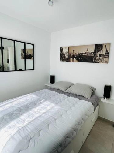 duże łóżko w białym pokoju z 2 oknami w obiekcie Maison 4 personnes avec jacuzzi w mieście Marignane