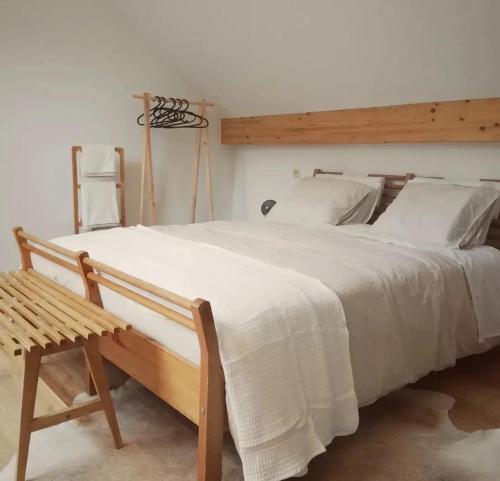 a bedroom with a large white bed and a wooden bench at Paulette à bicyclette in Méry