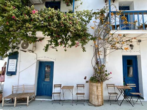 a white building with blue doors and tables and chairs at Chez Cécile Home in Mochlos