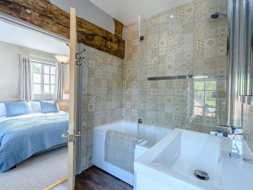 a bathroom with a bed and a tub and a sink at The Creamery in Alrewas