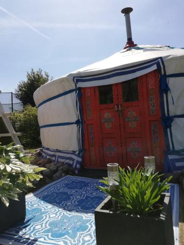a yurt with a red door and some plants at T'eiberveld Yurt verhuur Noord-Sleen in Noord-Sleen