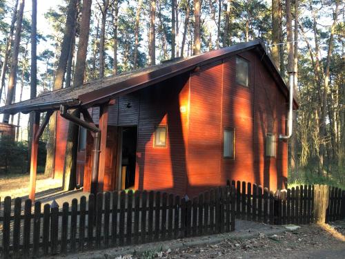 una pequeña cabaña en el bosque con una valla en Rudno 48 Domek Letniskowy, en Rudno