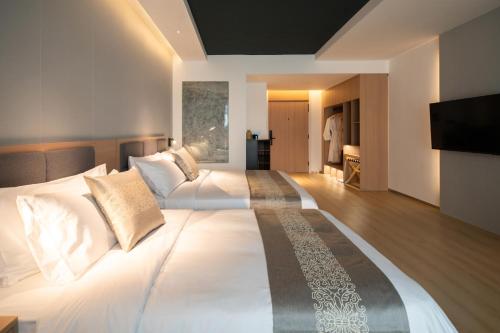 a bedroom with a large white bed with a flat screen tv at JI HOTEL 