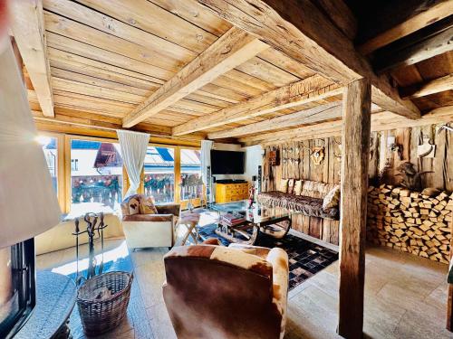 a living room with wooden ceilings and a room filled with furniture at Chasa Engadina in Sent