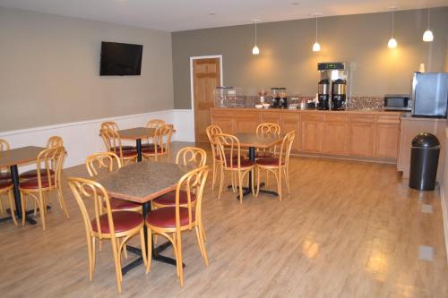 a dining room with tables and chairs and a kitchen at Sky Lodge Inn & Suites - Delavan in Delavan