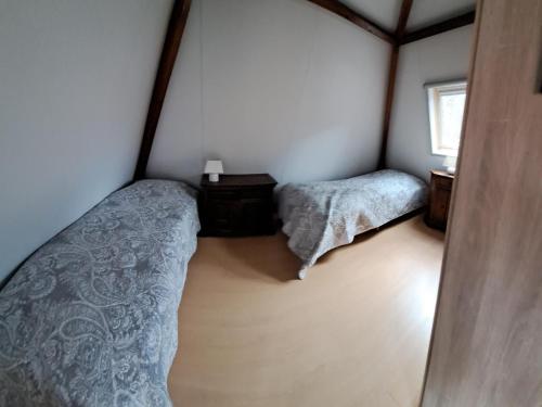 een kleine slaapkamer met 2 bedden en een raam bij Onder de Boomen in Bergen