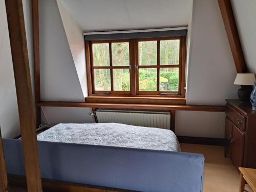 een slaapkamer met een bed en een raam bij Onder de Boomen in Bergen