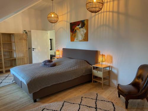um quarto com uma cama e uma cadeira e duas luzes em Vakantiewoningen Bienvenue, Le Pont em Lanaken