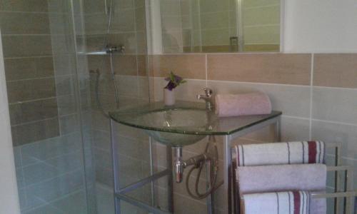 y baño con lavabo de cristal y ducha. en Gîtes Lalaurie, en Sauveterre-la-Lémance