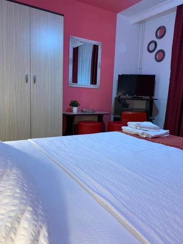 - une chambre avec un lit blanc et des murs roses dans l'établissement Casa Neamtu, à Băile Herculane