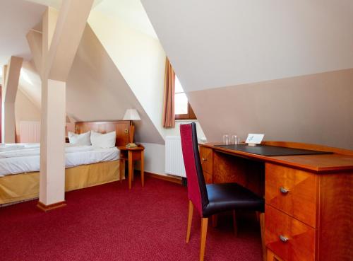 a bedroom with a bed and a desk with a chair at Hotel und Restaurant Haus Sajons in Plau am See