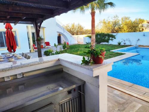 a backyard with a swimming pool and an outdoor grill at Villa Kenais Sunset in Taguermess