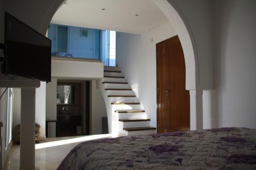 a bedroom with a bed and a staircase with a television at Villa Kenais Sunset in Taguermess