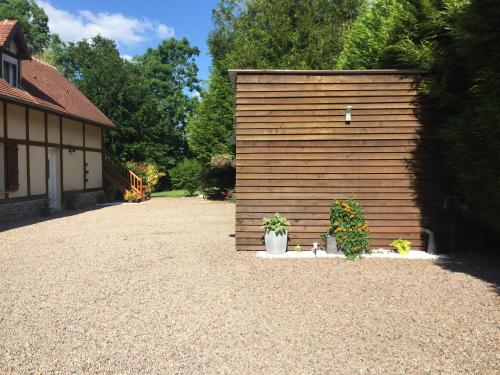 a wooden garage with two plants in front of it at Gîte Bien-être in Yquebeuf