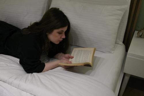 a woman laying in bed reading a book at 4SeasonsGea , Cozy Studio In Central Position , Tirana in Tirana