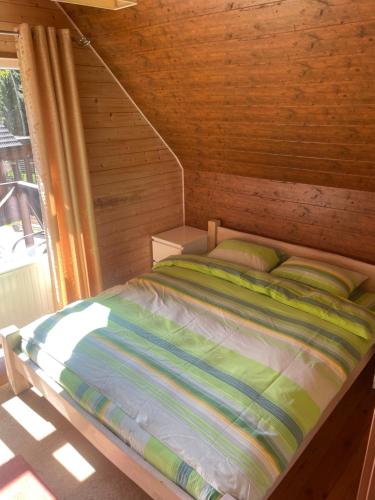 a bed in a wooden room with a window at Rustic private Cabin in woods w/ Sauna & Pool in Vilnius