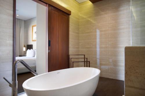 a bath tub in a bathroom with a bedroom at The Claremont Luxury Villas in Seminyak