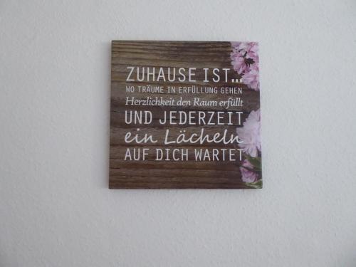 a wooden sign on a wall with flowers on it at City-Apartment Lüdenscheid in Lüdenscheid