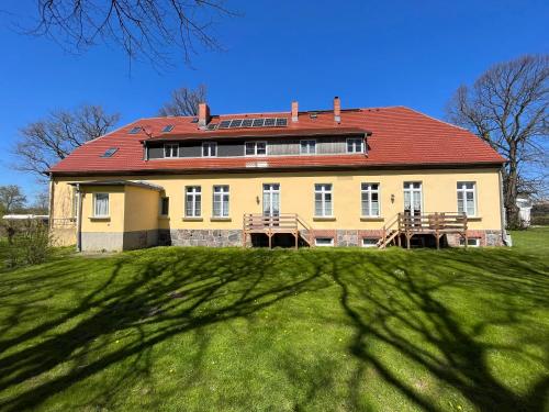 a large yellow house with a red roof on a green field at Meerzauber in Altenkirchen