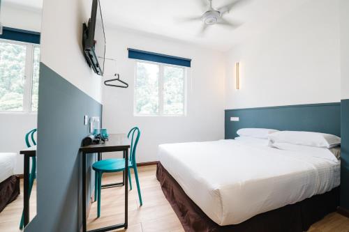 a bedroom with a bed and a desk with a chair at The Concept Hotel KL - Batu Caves in Batu Caves