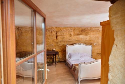 a bedroom with a bed and a desk and a mirror at Domaine de Cantegrel - Gîtes de Charme et Suite Troglodyte en Périgord in Vitrac