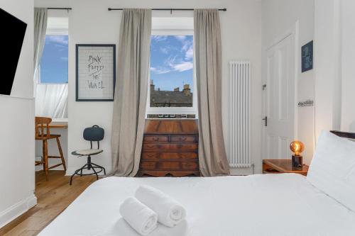 a bedroom with a white bed and a window at spacious flat, close to the city centre with scenic views in Edinburgh