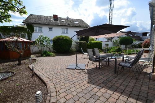a patio with a table and chairs and an umbrella at Zauber der Pfalz in Römerberg