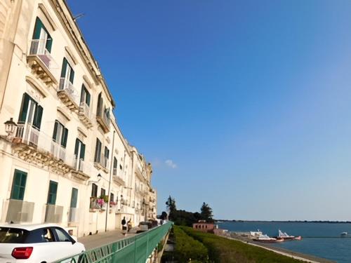 a white car parked next to a building next to the water at Camere A’ Marina in Siracusa