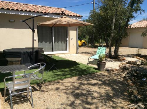 un patio avec une table et un parasol dans l'établissement Au Petit Bueix, à Sillans-la-Cascade