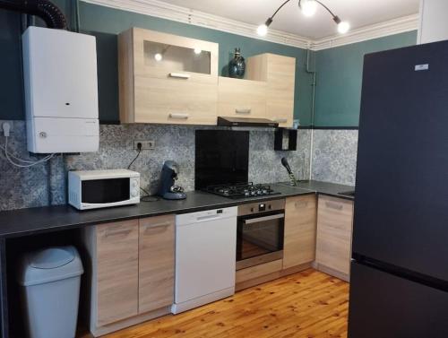 a kitchen with wooden cabinets and a white microwave at Appartement Foch in Le Puy en Velay