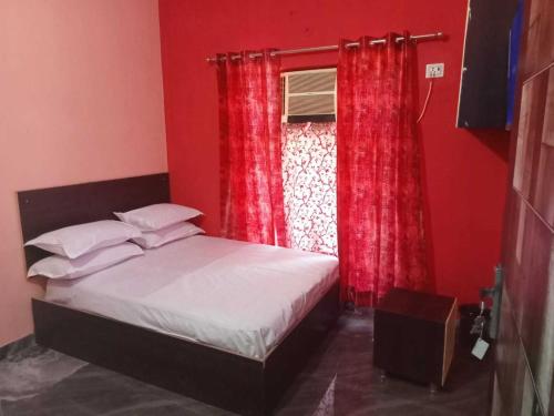 1 dormitorio con 1 cama y una ventana con cortinas rojas en POP VS White House, en Meerut