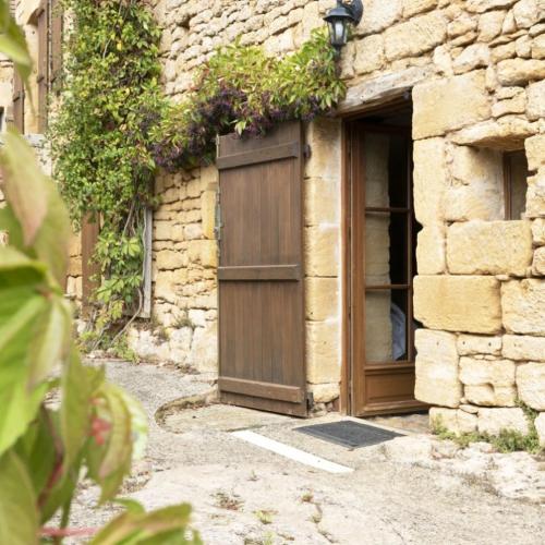 a building with a wooden door and a window at Domaine de Cantegrel - Gîtes de Charme et Suite Troglodyte en Périgord in Vitrac