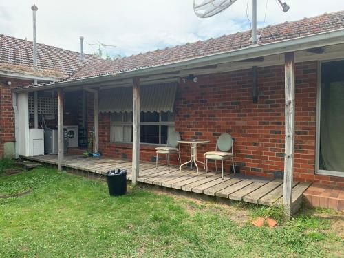 a house with a wooden porch with two chairs and a table at Chadstone Holiday K Studio in Chadstone